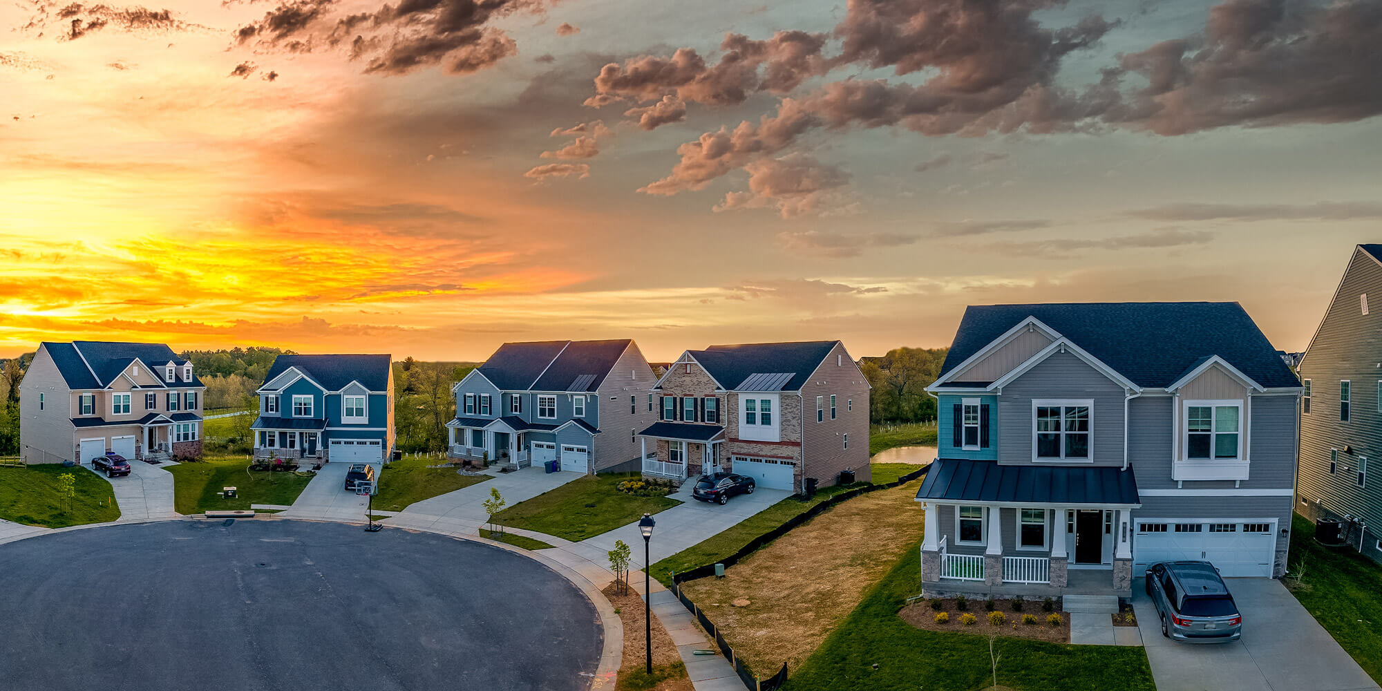 The sun sets over a cul-de-sac of two-story homes.