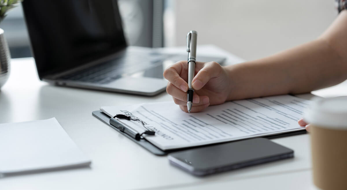 Woman is sitting at a desk writing up a contract.